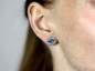 Mobile Preview: Silver and blue turquoise like ocean waves stud earrings worn on one ear.