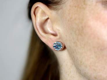 Silver and blue turquoise like ocean waves stud earrings worn on one ear.