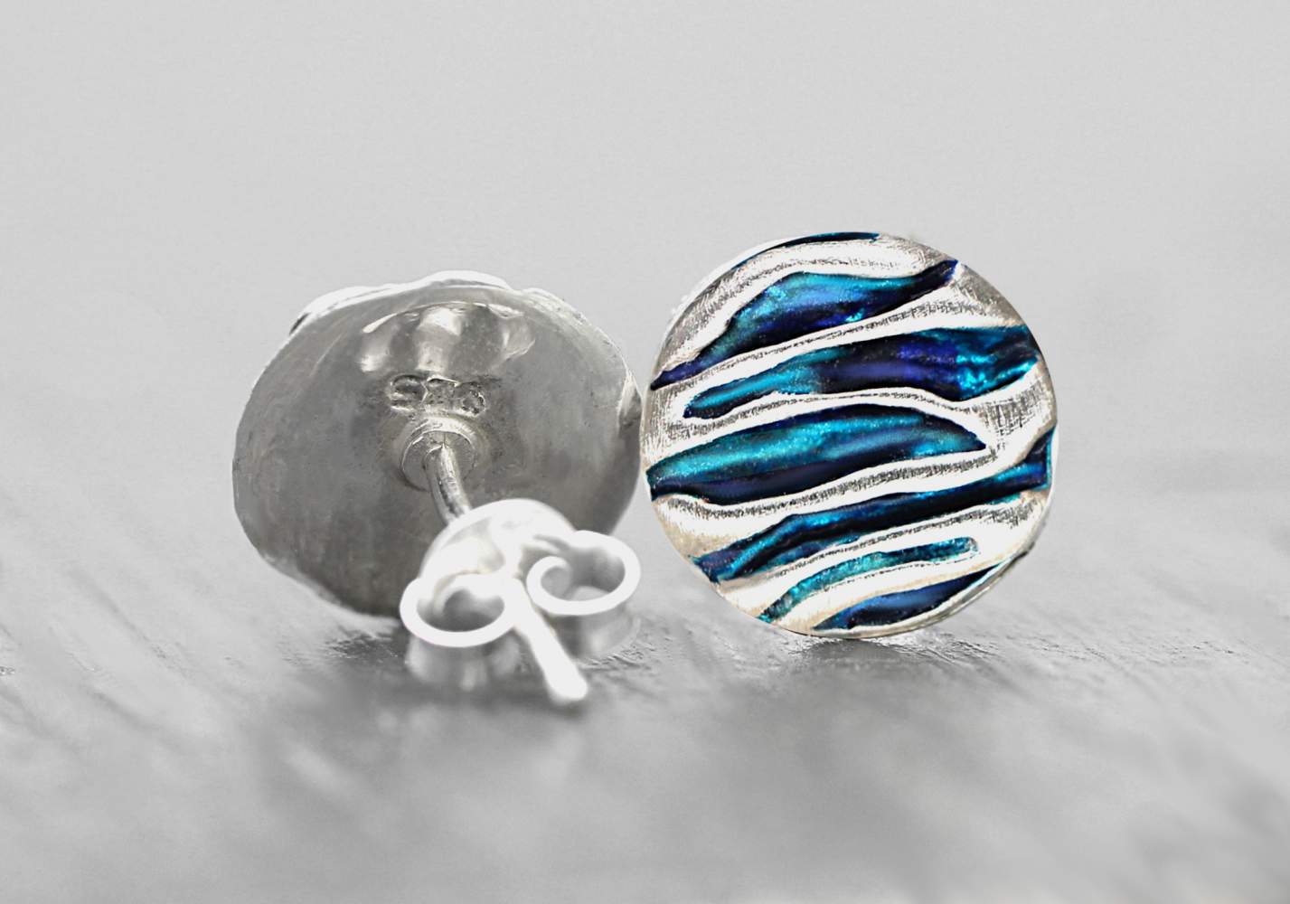A pair of silver and blue turquoise like ocean waves stud earrings. Detail back and front